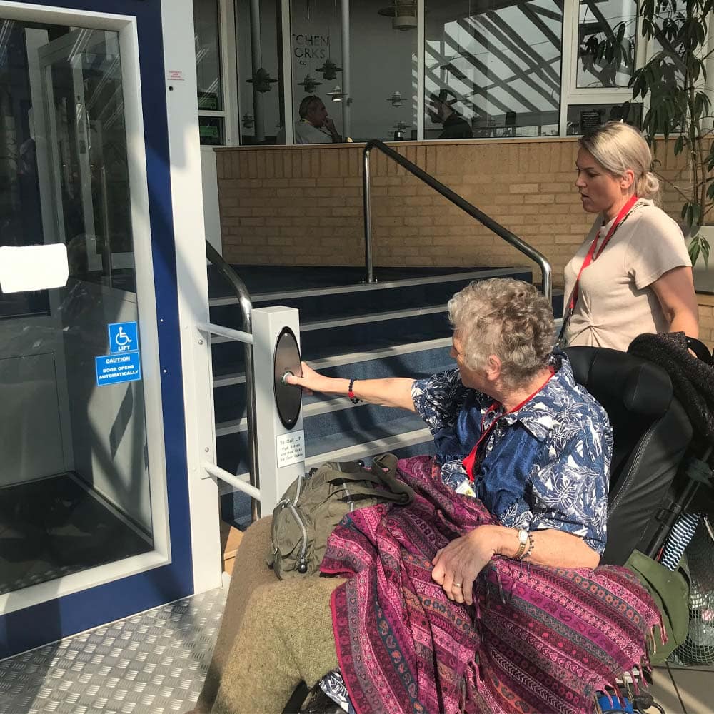 Woman in wheelchair pushing button of accessible lift